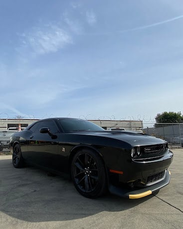 Black Dodge Challenger with custom wheels parked on concrete lot
