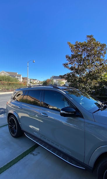 Gray SUV parked on suburban street with blue sky and tree