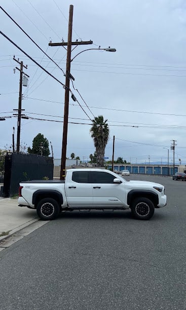 White pickup truck parked on urban street with power lines and palm tree