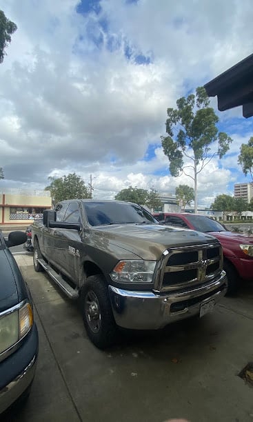 Large gray Ram pickup truck parked in lot with cloudy sky