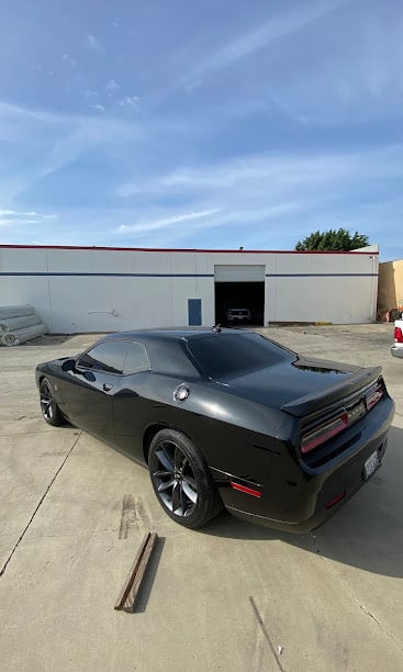 Black Dodge Challenger parked in an industrial parking lot