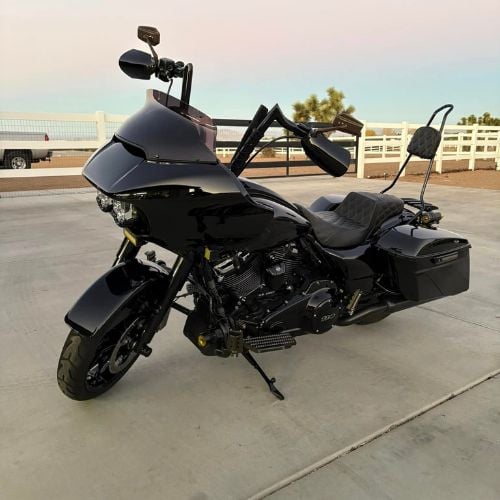 Black touring motorcycle parked on concrete with white fence background